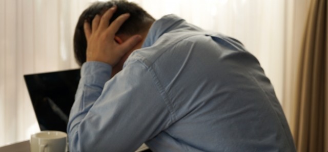 パソコンに向かって悩んでいる人